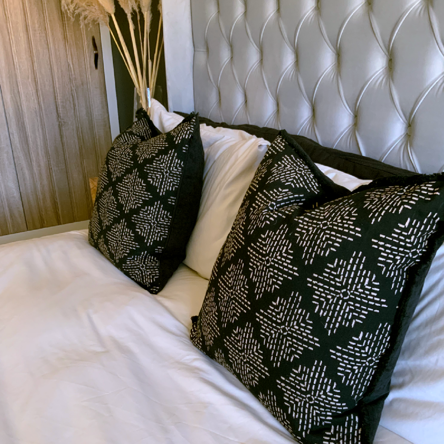 Black Cushion, feather cushion, large cushion. The Mila cushion is a luxurious addition to any living space, featuring a large feather-filled design with a cream embroidery pattern on a black background and a black fringe edging for added sophistication. With dimensions measuring 50cm x 50cm, this cushion is sure to make a statement in your home and perfect cushion for your bed or sofa. Available as a filled cushion.